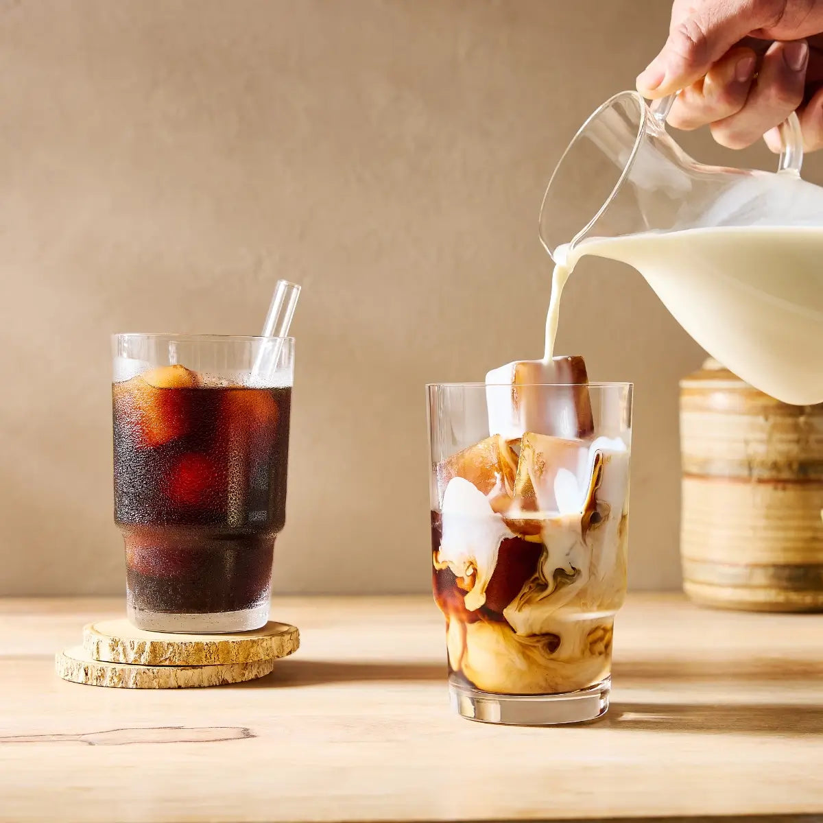 Pouring milk into a glass of premium iced coffee by Mt. Comfort Coffee