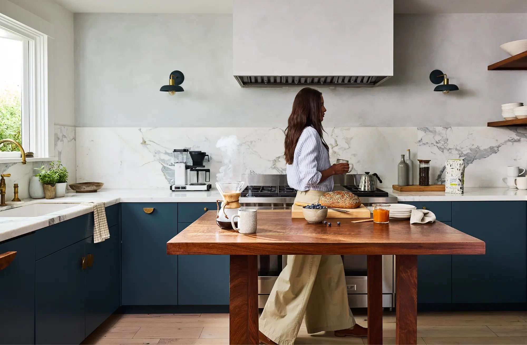 Woman walking in kitchen with Mt. Comfort premium coffee in cup